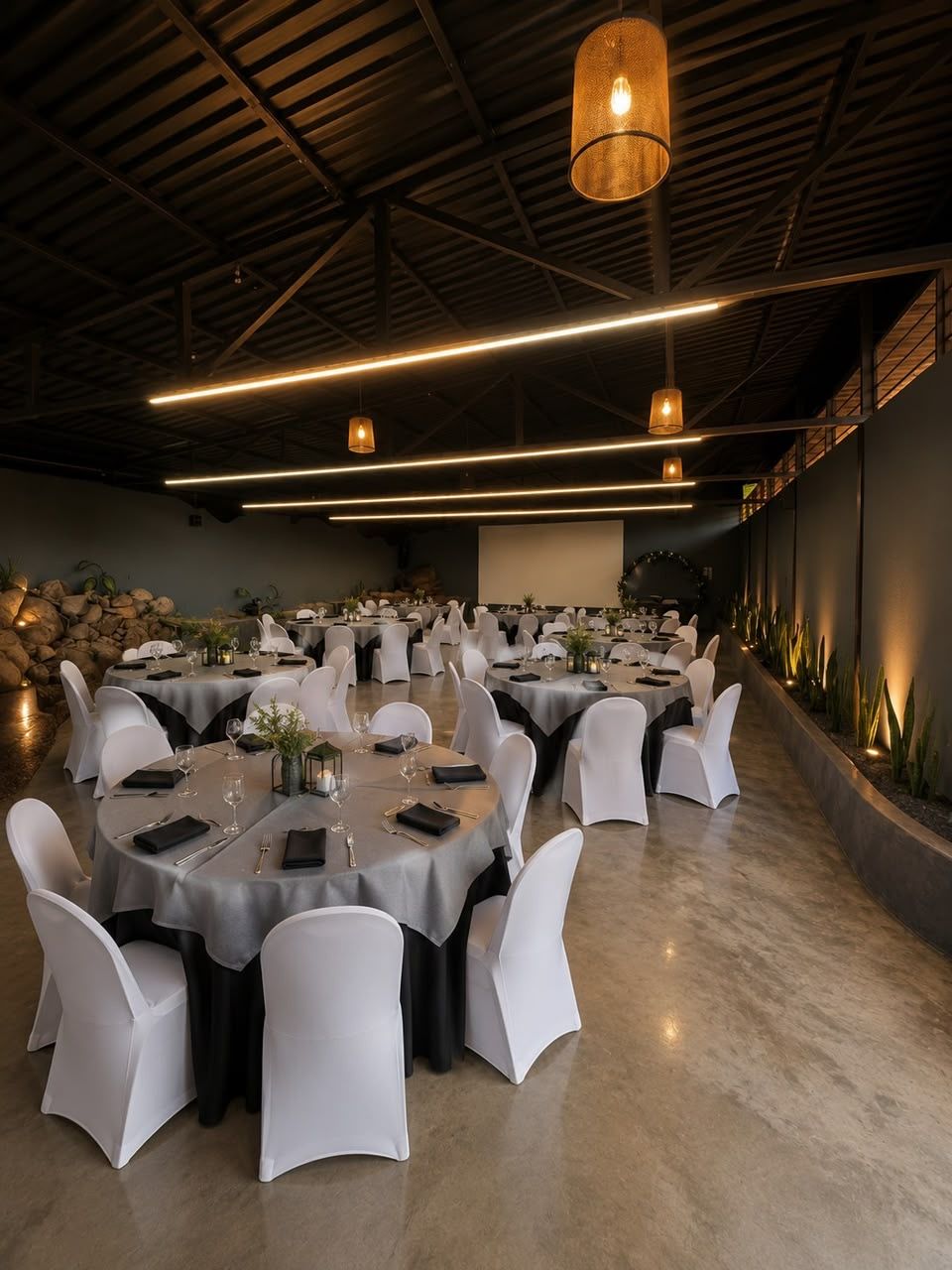 Salón del Centro Mirador montado en mesas redondas, techo de estructura vista y jardín interior de piedra